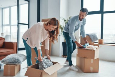 Yeni bir daireye taşınırken gülümseyen ve eşyalarını boşaltan mutlu genç çift.