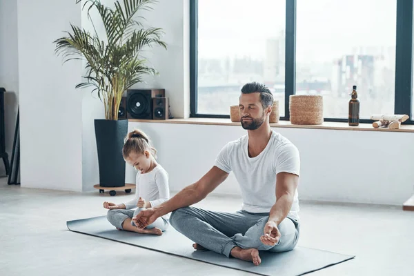 Padre e figlia che fanno yoga mentre sono seduti in posizione di loto a casa — Foto Stock