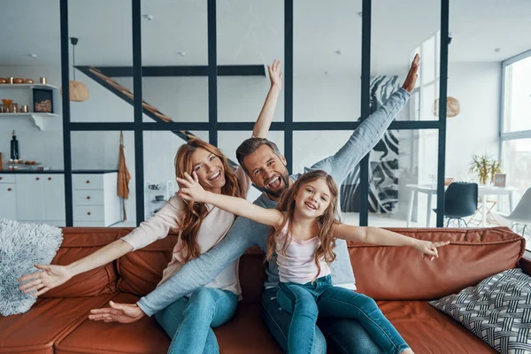 Lekfull ung familj sträcker ut sina händer och tittar på kameran samtidigt som de förenas hemma — Stockfoto