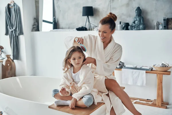 Happy young couple in bathrobes smiling and cleaning teeth while doing morning routine — Stock Photo, Image