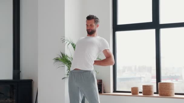 Hombre joven guapo haciendo ejercicio de estiramiento antes de entrenar en casa — Vídeos de Stock