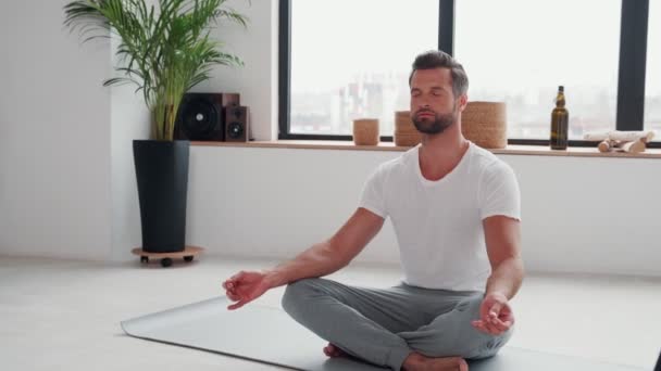 Hezký mladý muž dělá jógu se zavřenýma očima — Stock video