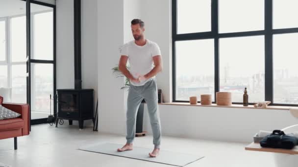 Hombre joven guapo haciendo ejercicio de estiramiento antes de entrenar en casa — Vídeos de Stock