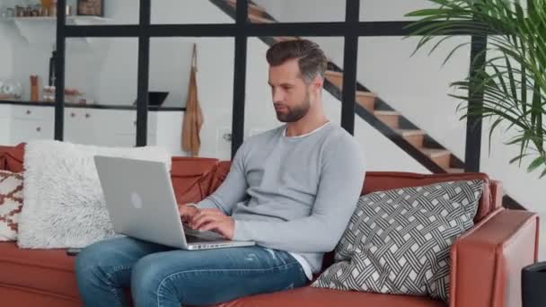 Jeune homme se détendre après le travail à la maison tout en étant assis sur le canapé — Video