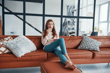 Televizyon seyreden ve patlamış mısır yiyen genç bir kadın.