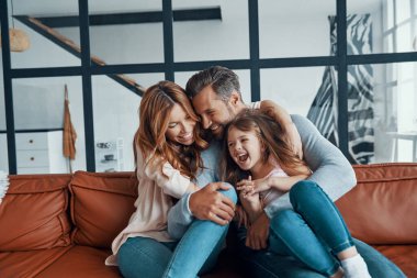 Anaokulu çağında mutlu, genç bir aile. Birbirlerine bağlanırken gülümsüyorlar.