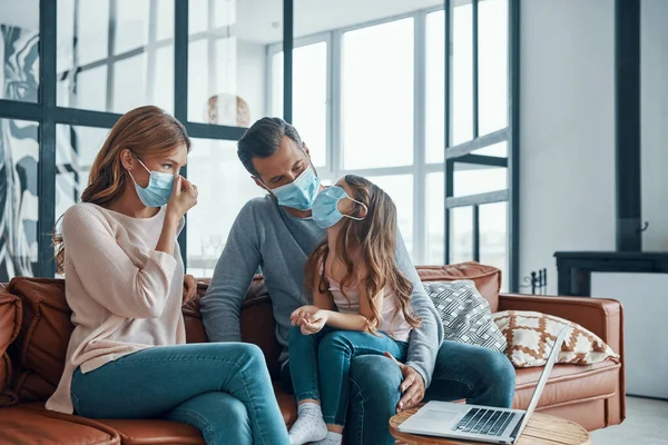 Young family wearing protective face masks while bonding together at home — Stock Photo, Image