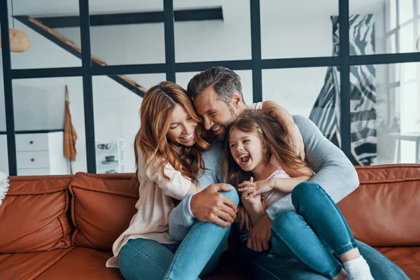 Felice giovane famiglia con ragazza in età prescolare sorridente mentre si legano insieme — Foto Stock