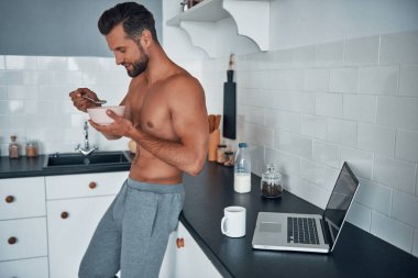 Güzel, genç, üstsüz, kahvaltı ederken, mutfakta dikiliyorsun..