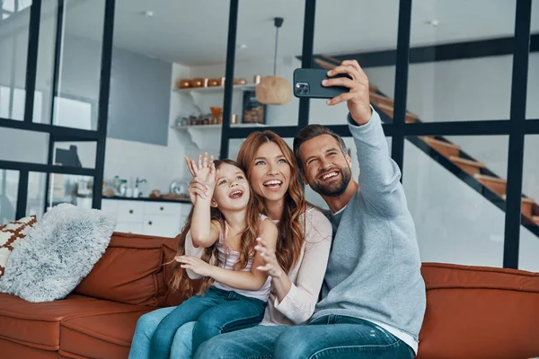 Οικογένεια χαμογελά και κάνει selfie από έξυπνο τηλέφωνο, ενώ περνούν το χρόνο τους στο σπίτι — Φωτογραφία Αρχείου