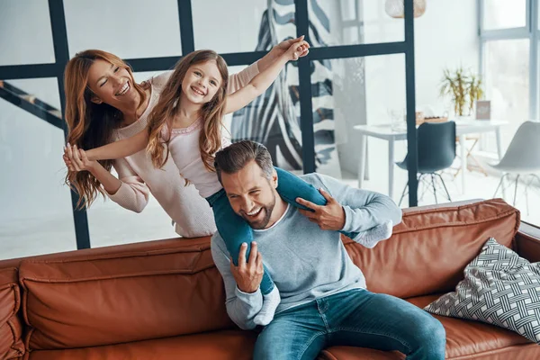 Vrolijke jonge familie hechting samen terwijl zitten op de bank thuis — Stockfoto