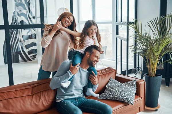 Vrolijke jonge familie glimlachend en omhelzend terwijl het binden van samen thuis — Stockfoto