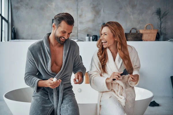 Loving young couple in bathrobes cleaning teeth while doing morning routine — Stock Photo, Image