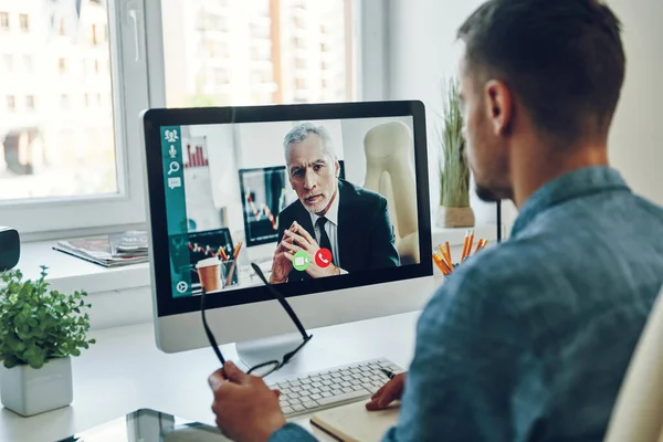 Sebevědomý Mladý Muž Mluví Kolegou Prostřednictvím Videohovoru Zatímco Sedí Kanceláři — Stock fotografie