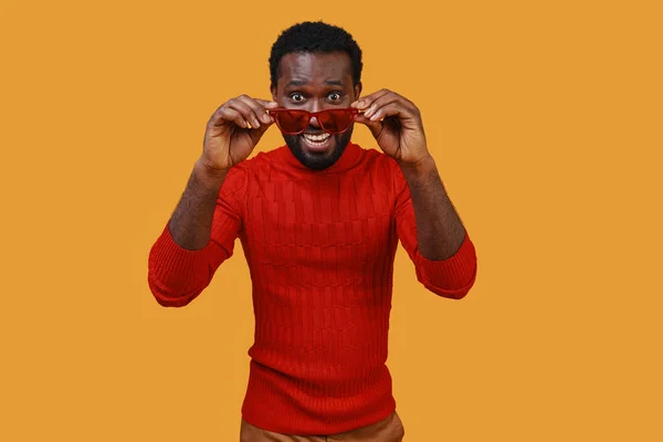 Handsome young African man in casual clothing looking at camera and adjusting eyeglasses — Stock Photo, Image