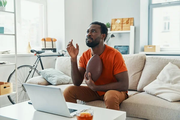 Joven africano sintiéndose emocionado por el juego mientras ve el deporte partido en casa — Foto de Stock