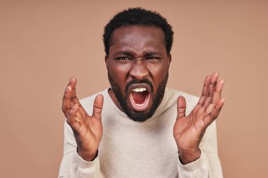 Kızgın genç Afrikalı gündelik giysiler içinde çığlık atıyor ve kameraya bakıyor.