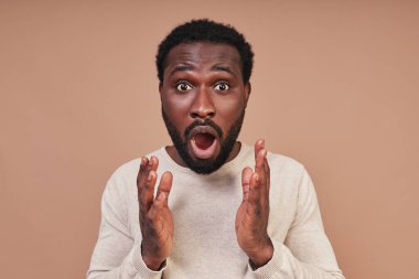 Sıradan giyinmiş, yüzünü ekşitmiş ve kameraya bakan Afrikalı genç bir adam.