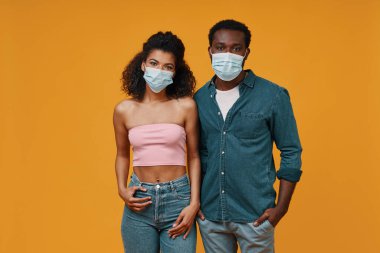 Koruyucu maskeli genç ve güzel Afrikalı çift kameraya bakıyor.