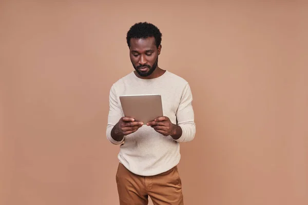 컴퓨터 태블릿을 사용하여 평상복을 입고 있는 신뢰할 만 한 젊은 아프리카 남자 — 스톡 사진