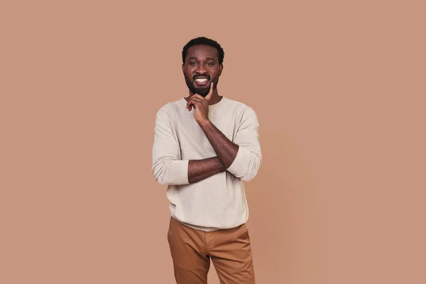 Schöner junger afrikanischer Mann in lässiger Kleidung blickt in die Kamera und lächelt — Stockfoto