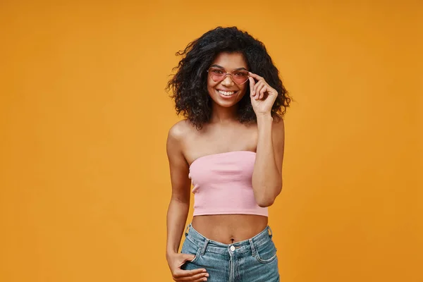 Hermosa joven africana con ropa casual ajustando sus gafas —  Fotos de Stock