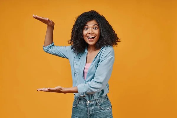 Beautiful young African woman in casual clothing pointing copy space and smiling — Stock Photo, Image