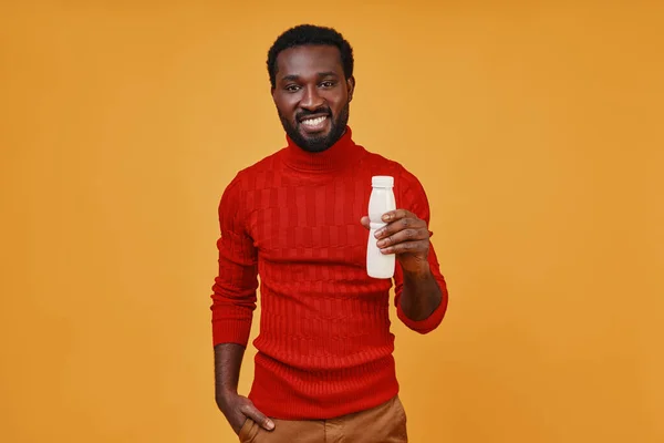 Stilig ung afrikansk man håller flaskan och tittar på kameran ler — Stockfoto