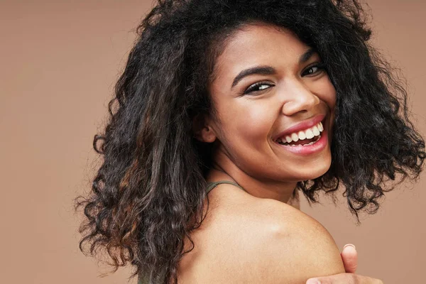 Beautiful young African woman smiling and looking over shoulder — Stock Photo, Image