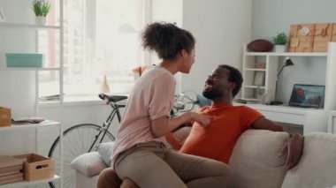 Genç Afrikalı çift evde vakit geçirirken kaynaşıyor ve gülümsüyor.