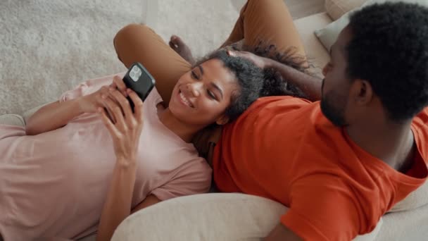 Vue du dessus de la jeune femme africaine utilisant un téléphone intelligent avec son petit ami — Video