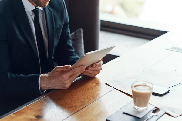 Închiderea unui tânăr om de afaceri în costum complet folosind tabletă digitală în timp ce stă în restaurant — Fotografie, imagine de stoc