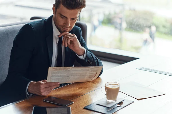 Handsome young businessman in full suit reading menu while sitting in the restaurant — Stock Photo, Image