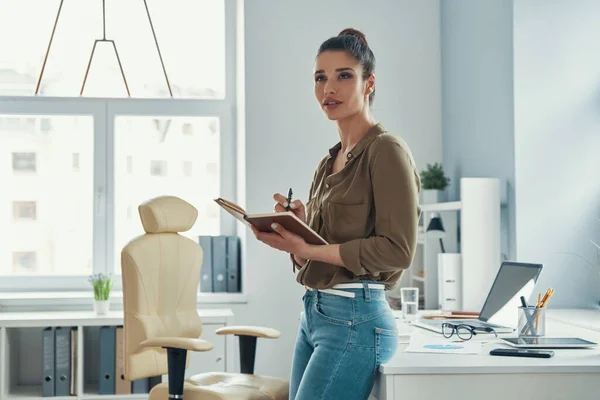 Beautiful young woman in smart casual wear smiling while standing in the office — Photo