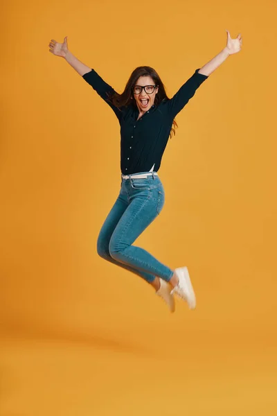 Full of length beautiful young women screaming and jumping against yellow background