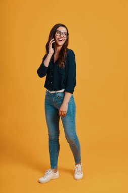 Full length of bbeautiful young woman in casual clothing smiling and talking on the phone