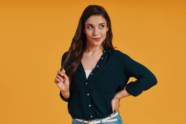 Attractive young woman in casual clothing twisting hair and smiling