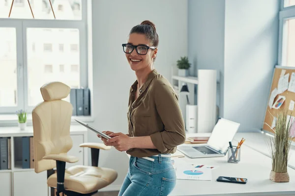 Beautiful young woman in smart casual wear smiling while standing in the office — Photo