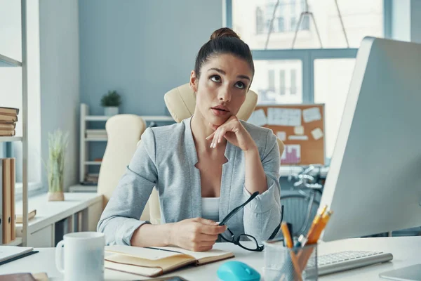 Stressed young woman in smart casual wear keeping head in hands while sitting in the office — Fotografia de Stock