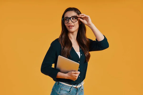 Confident young woman in smart casual clothing using digital tablet and adjusting eyewear — Stok fotoğraf