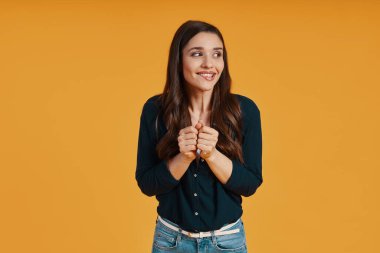 Surprised young woman in casual clothing using keeping hands together
