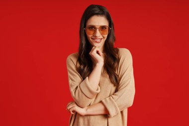 Beautiful young woman in casual clothing smiling and keeping hand on chin