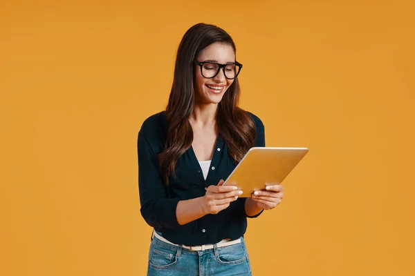 Confident young woman in smart casual clothing using digital tablet and smiling — Φωτογραφία Αρχείου