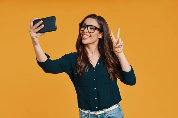 Happy young woman in casual clothing taking selfie and making a face — Stock Photo, Image