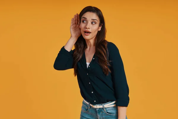 Playful young woman in casual clothing making a face while standing against yellow background — Stok fotoğraf