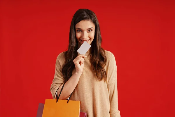 Beautiful young woman in casual clothing carrying shopping bag and credit card — Stock fotografie