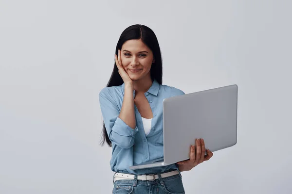 Attraktive junge Frau mit Laptop und lächelndem Blick in die Kamera — Stockfoto