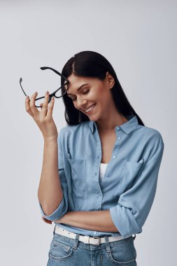 Gri arka planda dururken gülümseyen çekici genç kadın.