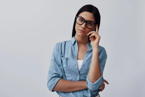 Attraktive junge Frau in Brille blickt vor grauem Hintergrund in die Kamera — Stockfoto