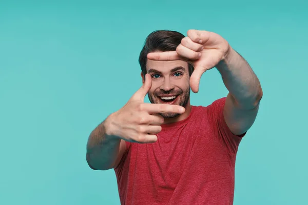 Bonito jovem sorrindo homem em roupas casuais olhando para a câmera e gesticulando — Fotografia de Stock